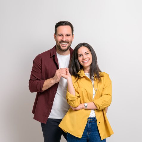 Portrait of romantic young boyfriend and girlfriend holding hands and smiling on white background